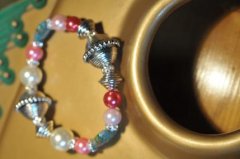 Sdt armbnd i bali style. Fine glas hjerter i blt med blomster. To hvide shellsperls og blandede rde og lyserde perler.Indeholder desuden  forslvet swarovski rondeller. Armbndet er lavet med elastik og mler ca. 19 cm.