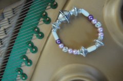 Balystyle armbnd med lyserd, lilla og hvide nuancer. Med bl.a forslvet swarovski rondeller som mellemled og forslvet kugler. Lavet med elastik og mler ca. 18 cm.