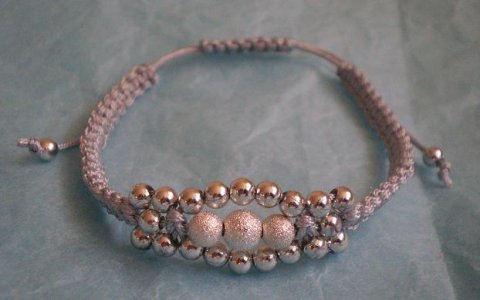 knyttet grt armbnd i tynd satin snor med forslvede perler.
