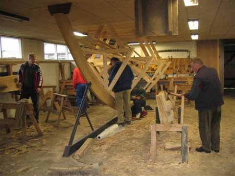 Agterstævnens stævntræ er sat op, skabeloner er anbrag, og Jørgen og Peter er igang med finbearbejdning. To bordplanker er under tilhugning af Kaj og Rasmus.